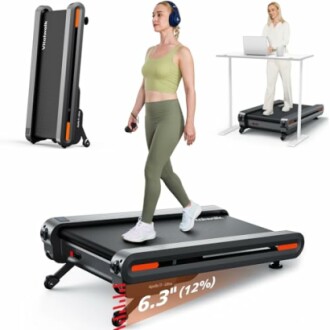 Woman using a compact treadmill while working at a desk, featuring a foldable design.